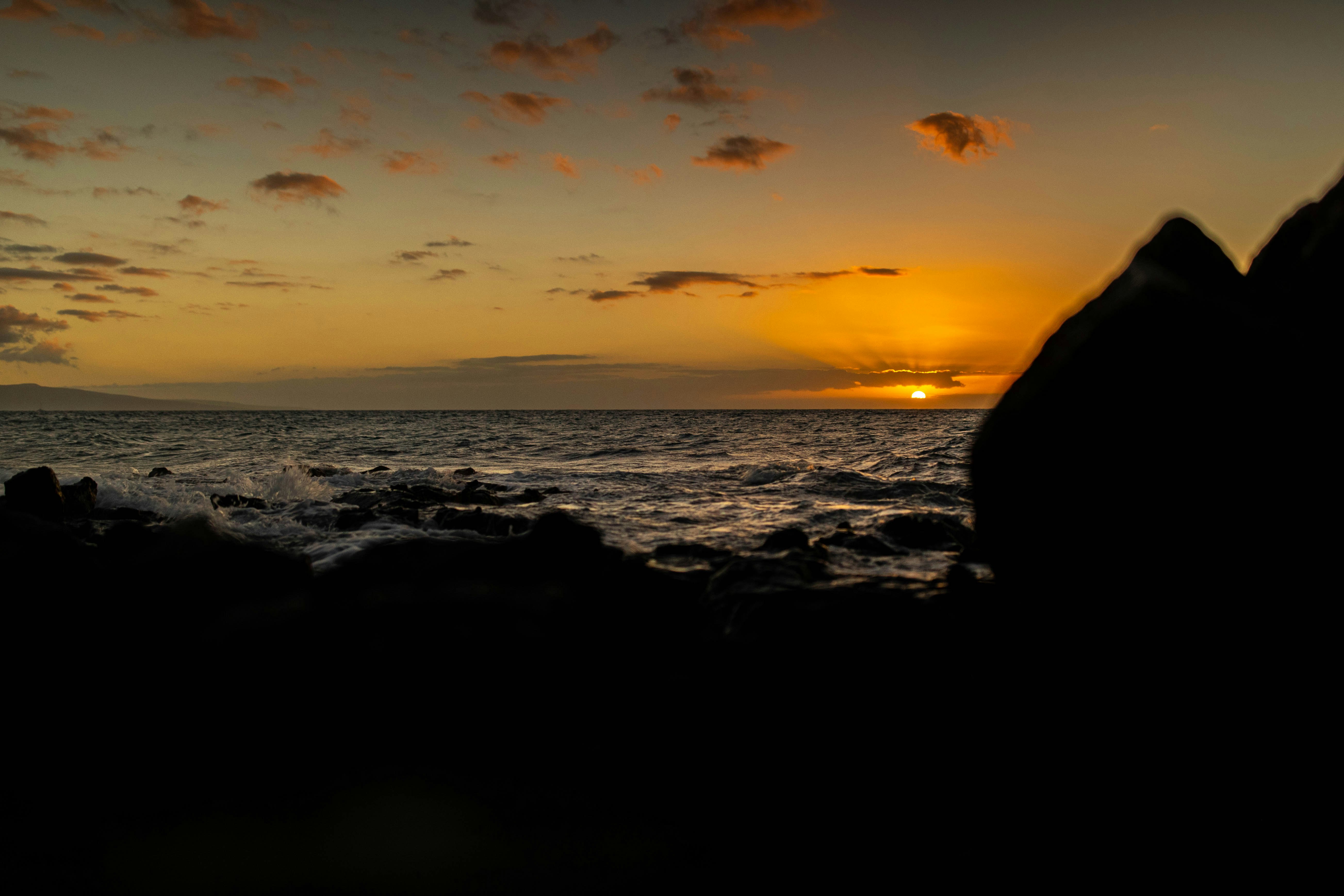 silhouette of rocks on beach during sunset