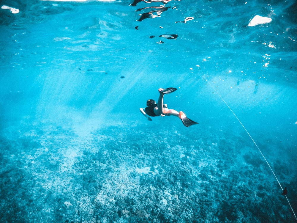 Mann in schwarzen Shorts schwimmt im Wasser