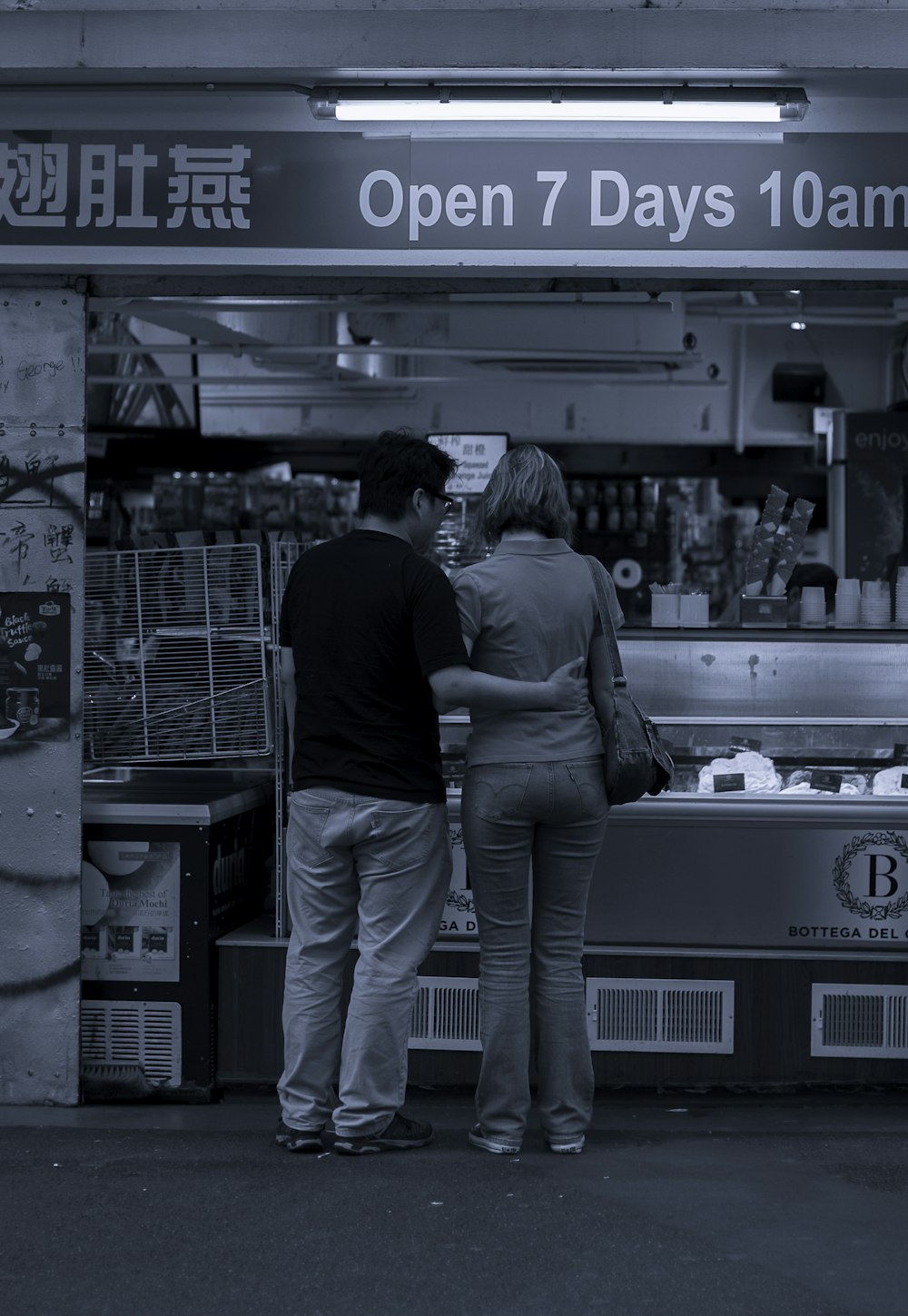 grayscale photo of man and woman standing in front of food counter