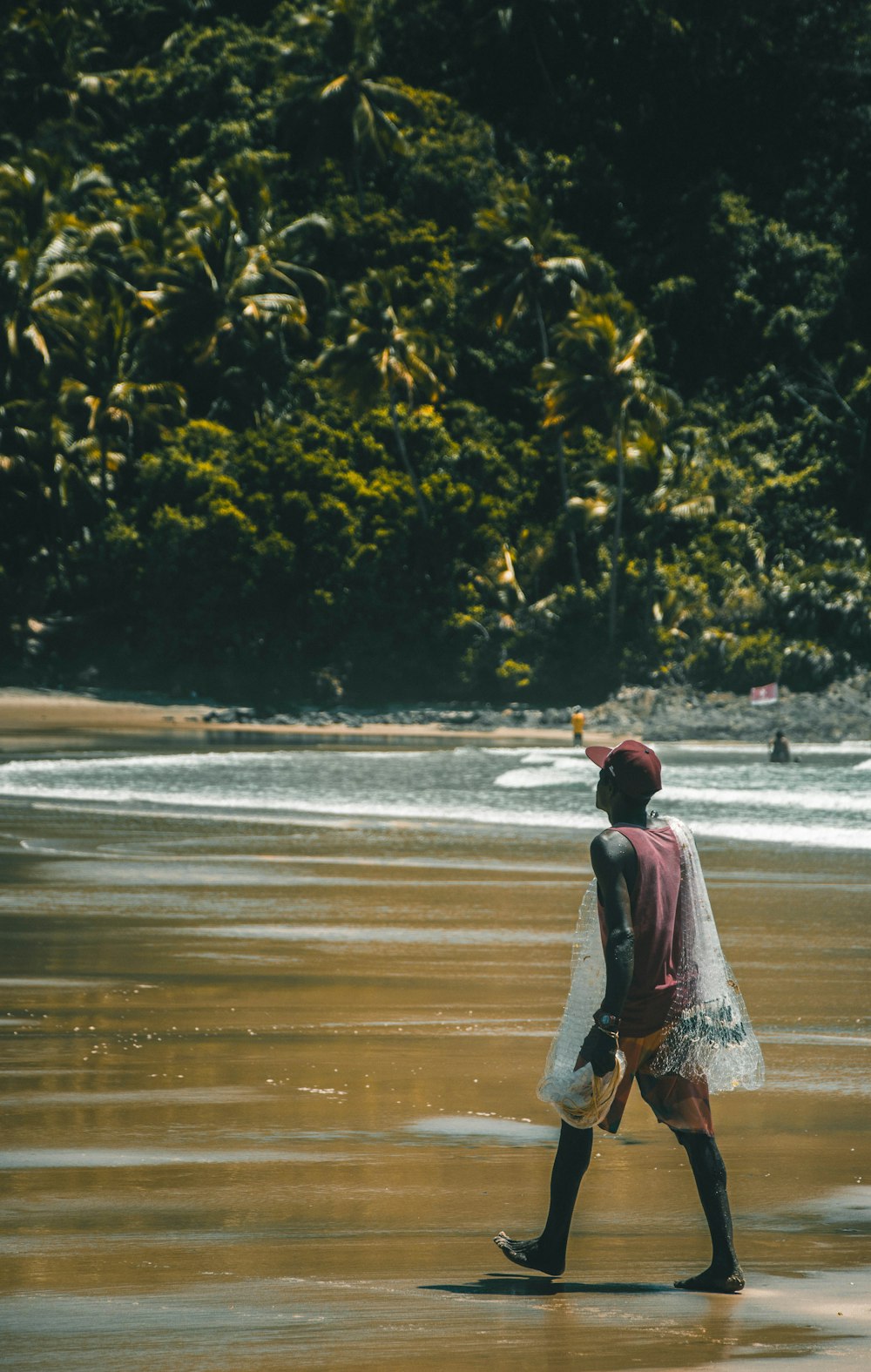 donna in vestito rosso e bianco che cammina in riva al mare durante il giorno