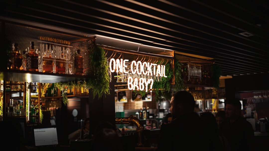 man in black shirt standing in front of brown wooden table, Neon