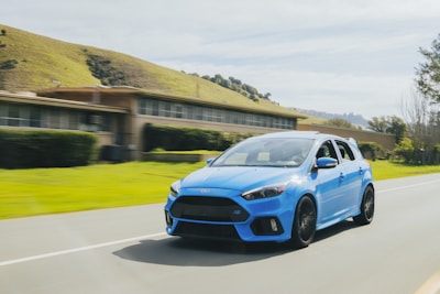 A futuristic flying car soaring above green hills under a clear blue sky.
