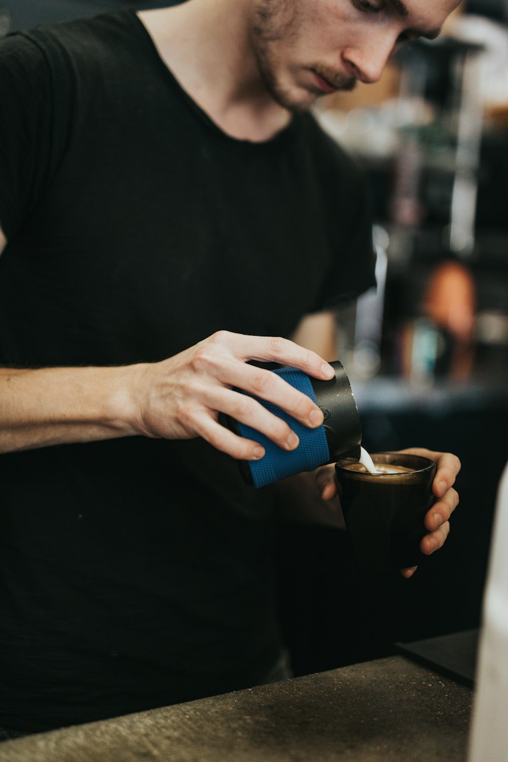 man in black crew neck t-shirt holding black ceramic mug