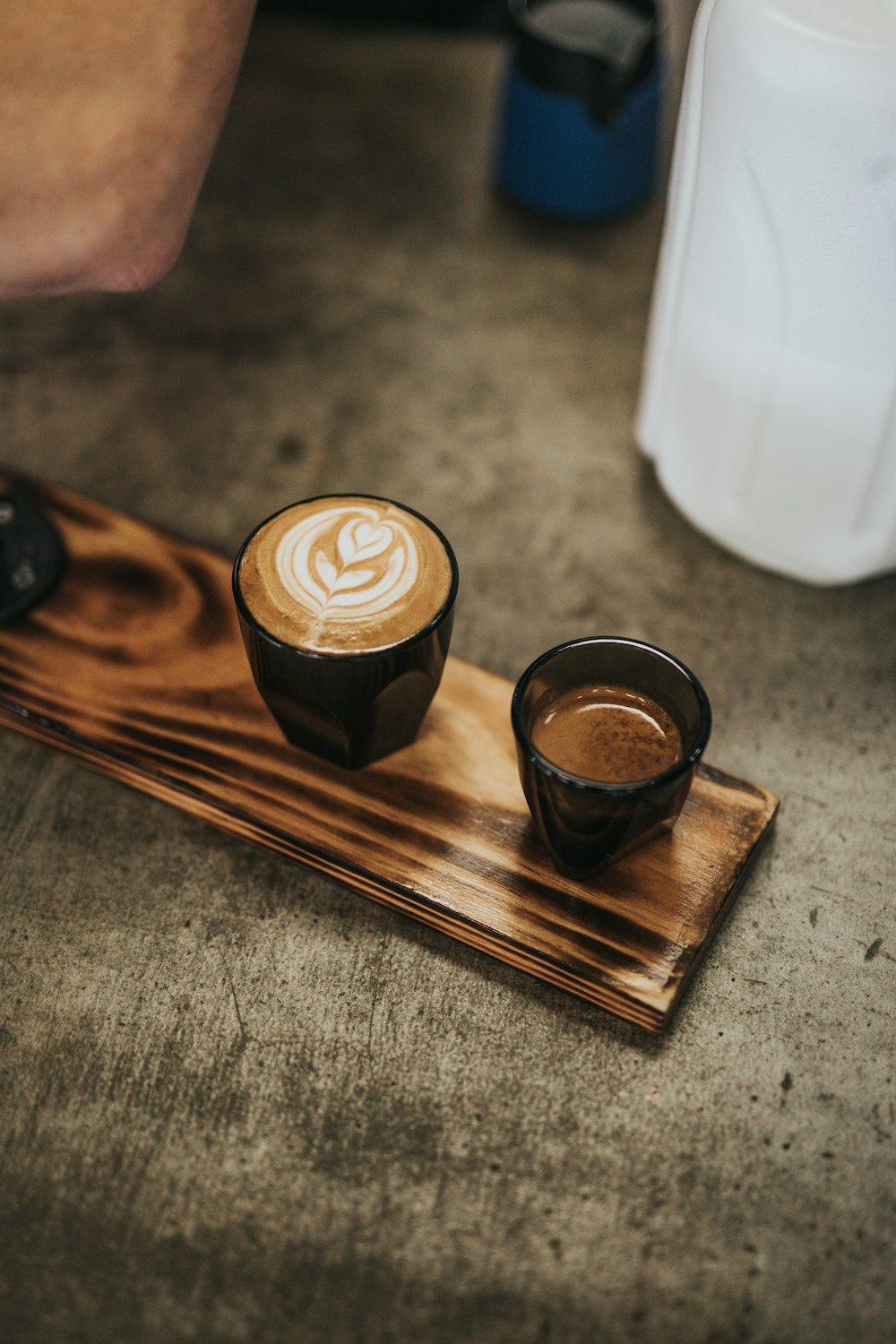 cappuccino in brown ceramic cup on brown wooden tray