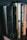 Several books stand side-by-side on a wooden shelf. The titles visible include religious and fiction genres, with one book titled 'The Living Bible' having a notably worn black cover. Other books have spines with dark, beige, and orange tones, and are authored by popular writers.