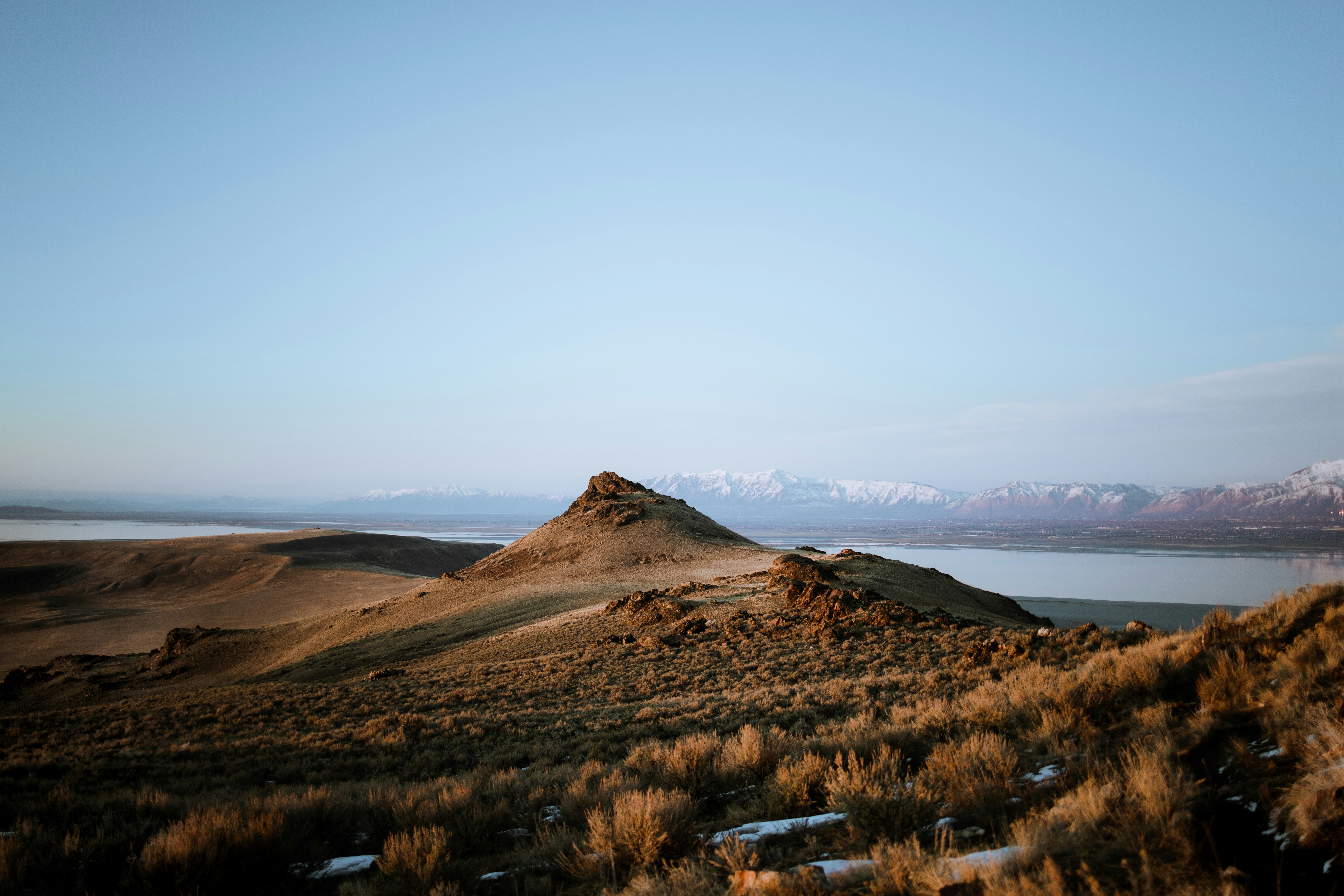 brown mountain near body of water during daytime