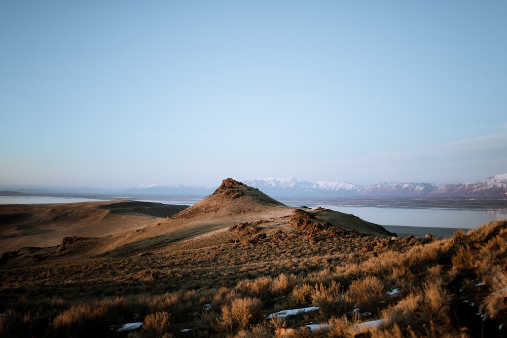 brown mountain near body of water during daytime