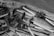A variety of metal and wooden farming tools are displayed on a surface. There are several hoes and metal implements with wooden handles. Various hooks and rings are shown on the left side. The scene is in black and white, adding a vintage or classic feel.