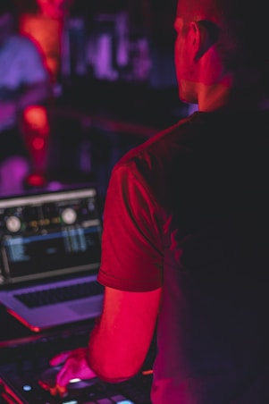 man in black t-shirt standing in front of dj mixer