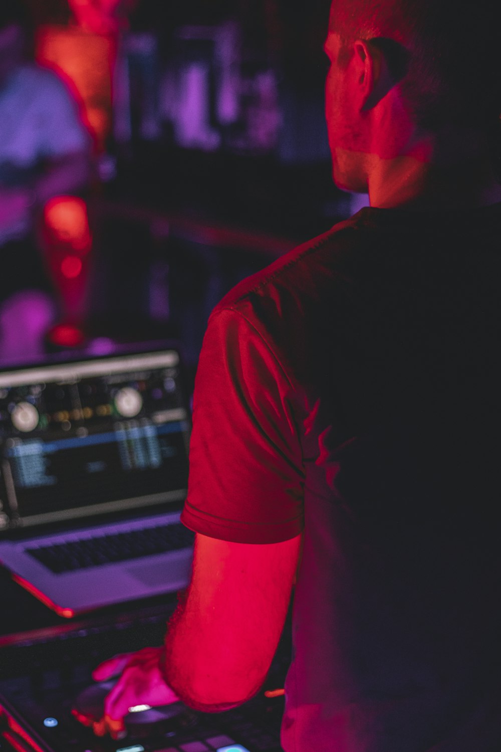 man in black t-shirt standing in front of dj mixer