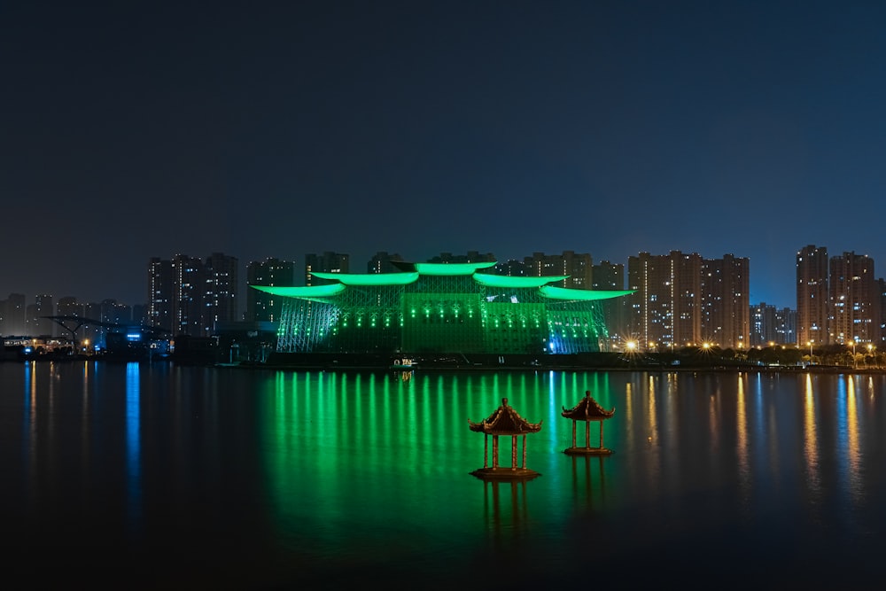 lighted city buildings near body of water during night time