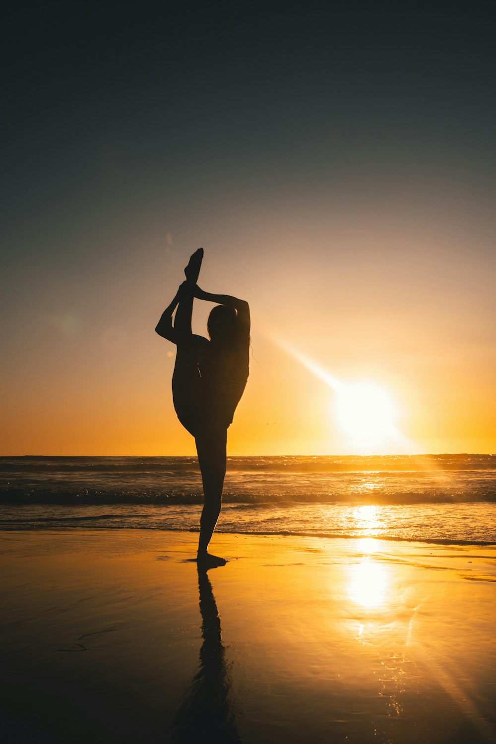 silhouette of woman standing on beach during sunset