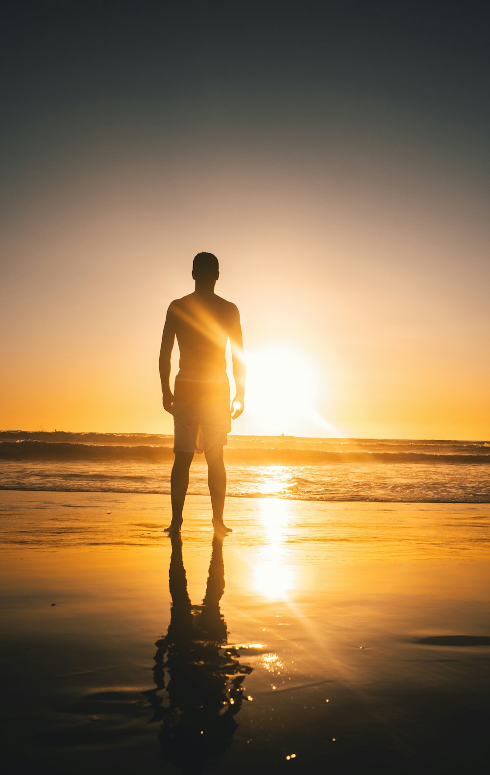 man in white long sleeve shirt standing on seashore during sunset