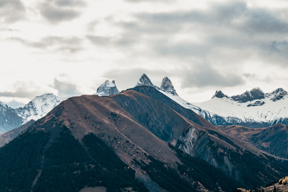 snow covered mountains under cloudy sky during daytime