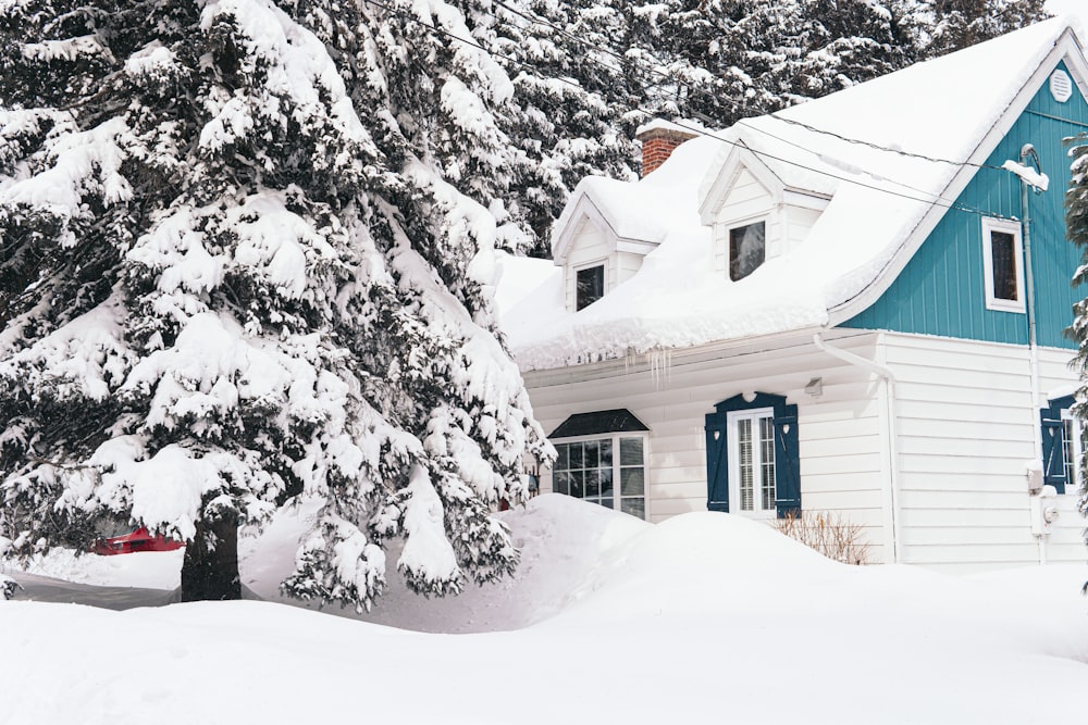 casa marrone coperta di neve vicino agli alberi durante il giorno