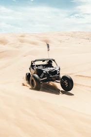 A bright red dune buggy kicking up sand on an adventurous off-road trail.