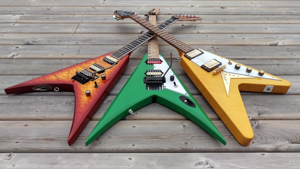 a group of three guitars sitting on top of a wooden floor