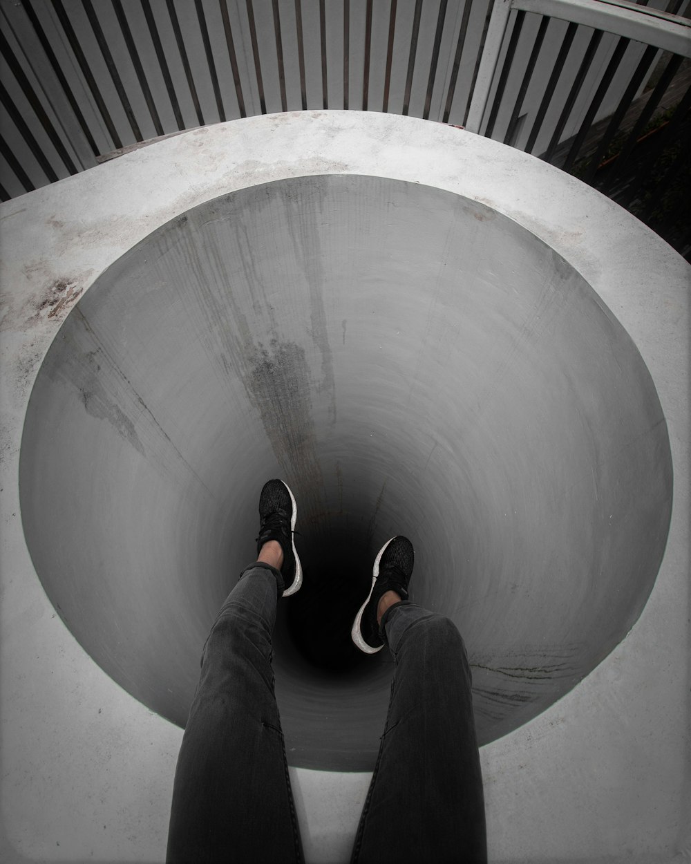 person in black pants and black shoes standing on gray concrete tunnel