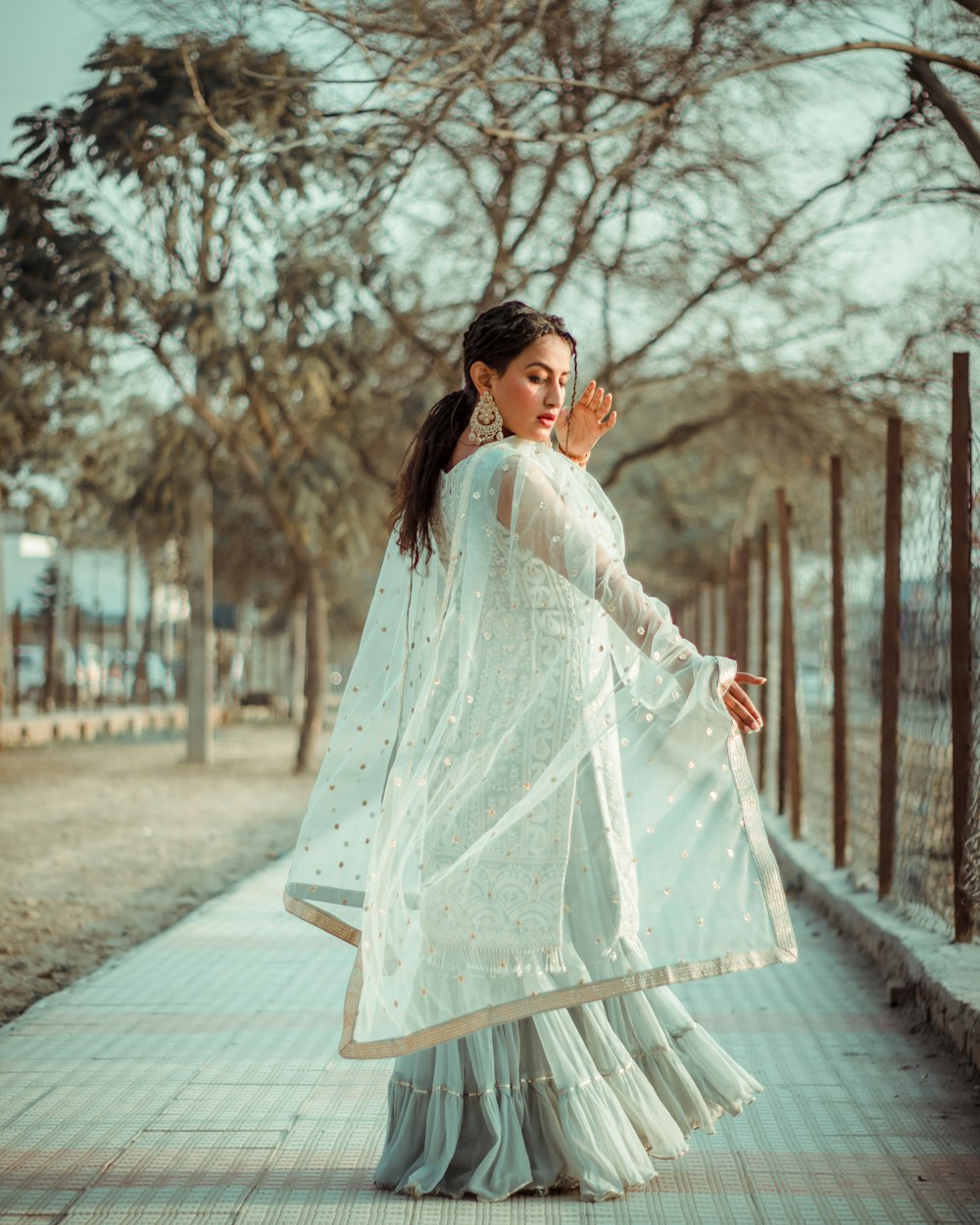 woman in white long sleeve dress standing on sidewalk during daytime