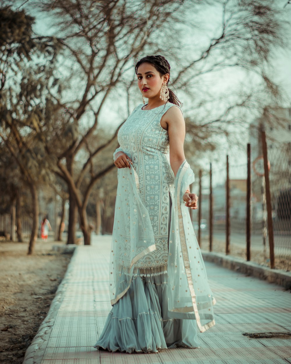 woman in gray sleeveless dress standing on gray concrete pathway during daytime