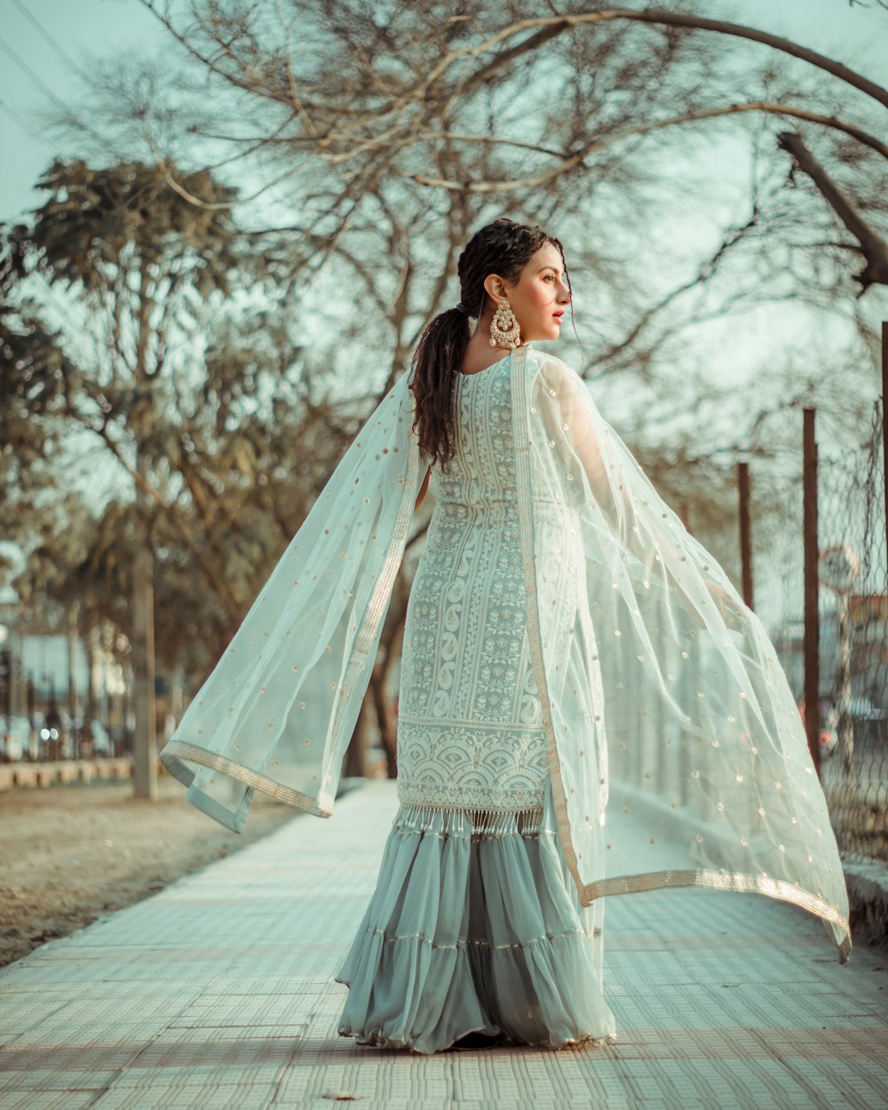 woman in white long sleeve dress standing on gray concrete pathway during daytime