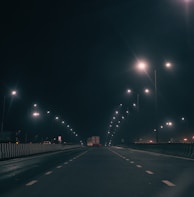 A nighttime highway scene with a truck’s headlights cutting through the dark, emphasizing long-haul dedication.