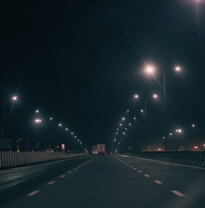 Nighttime shot of a Nobre Transportes Ltda truck driving on a highway with headlights on.