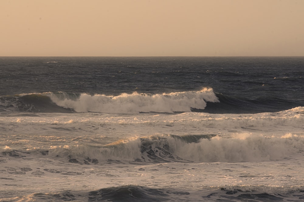 ocean waves crashing on shore during sunset