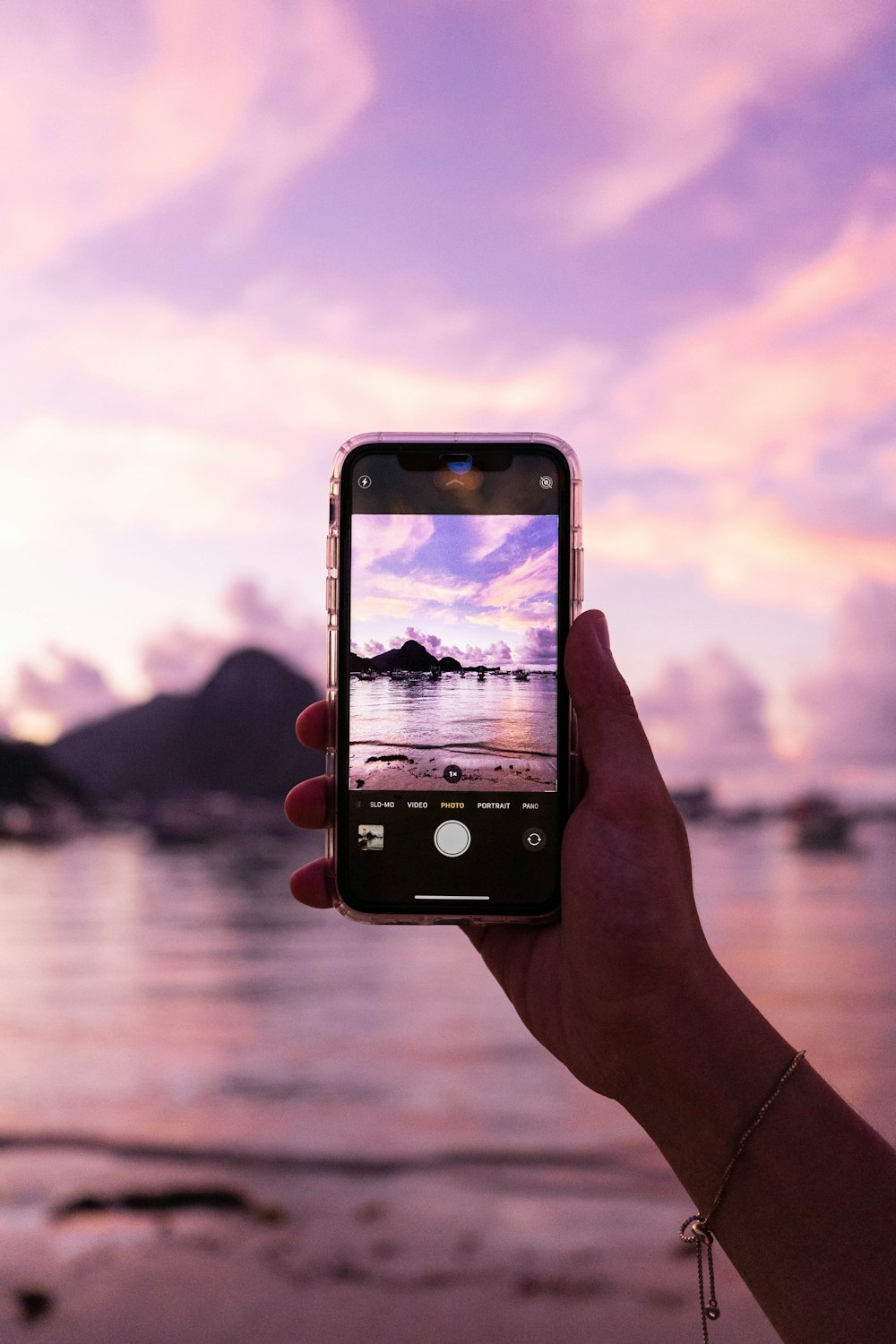 person holding iphone taking photo of body of water during daytime