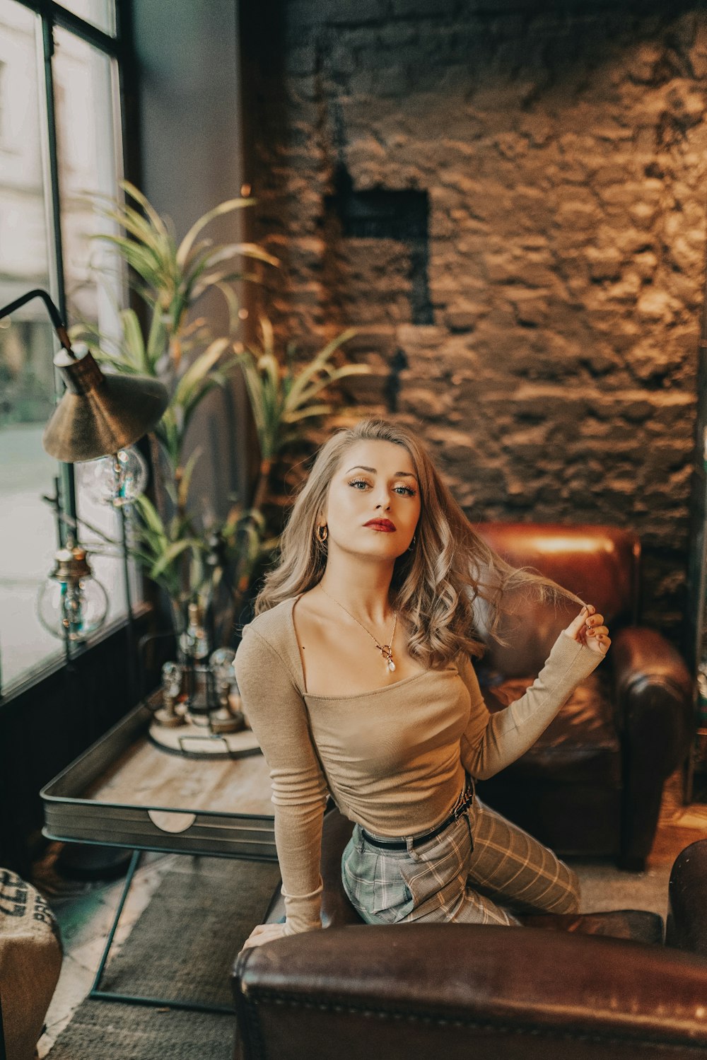 woman in brown long sleeve shirt and gray skirt sitting on brown leather couch