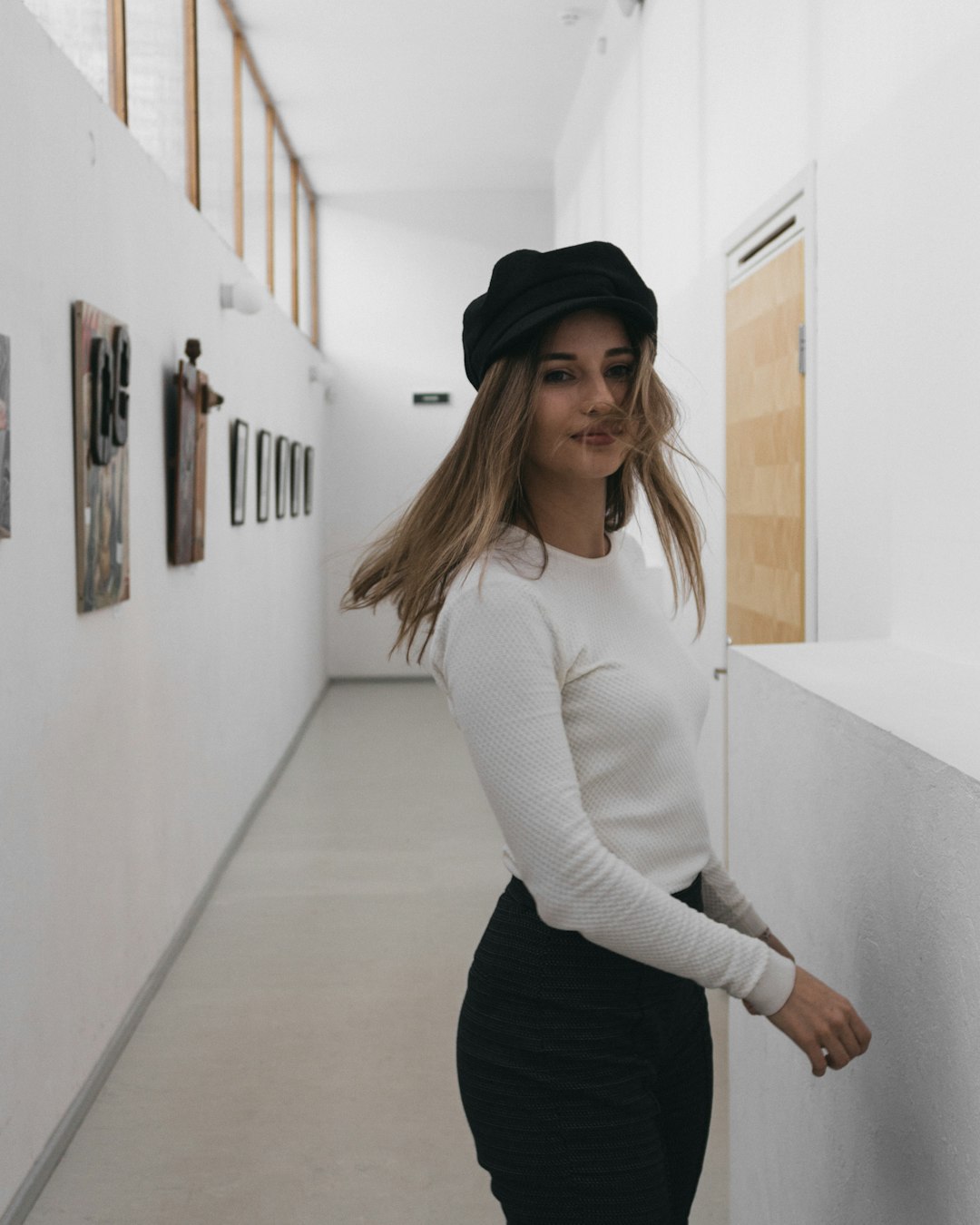 woman in white long sleeve shirt and black pants standing on hallway
