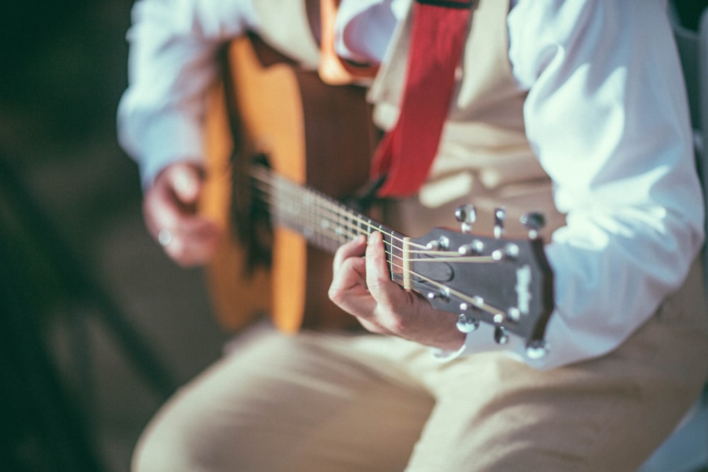 person playing brown acoustic guitar