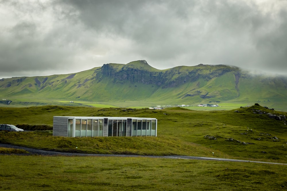 white and black house on green grass field near mountain under cloudy sky during daytime