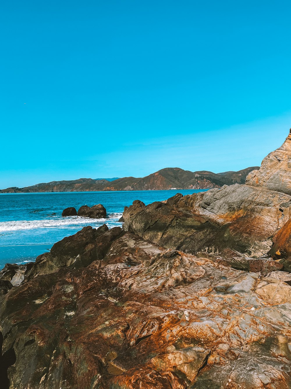 a man riding a surfboard on top of a rocky beach