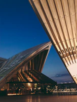 Architectural shot of a modern exterior with clean lines, stone grey surfaces, and warm beige highlights at dusk.