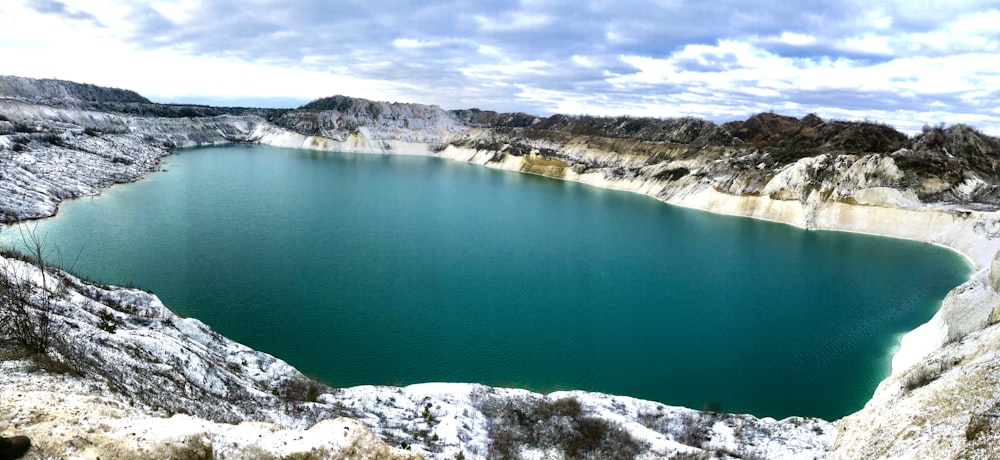 blue lake beside white and brown rocky mountain during daytime