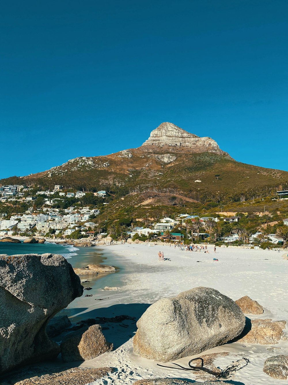 people on beach near mountain under blue sky during daytime