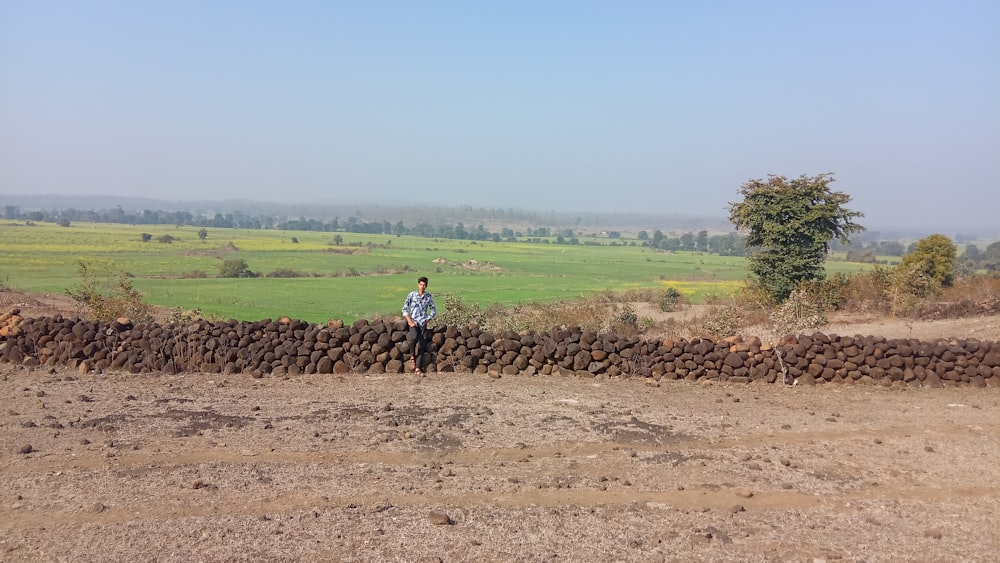 Persona con camisa azul caminando en un campo de tierra marrón durante el día