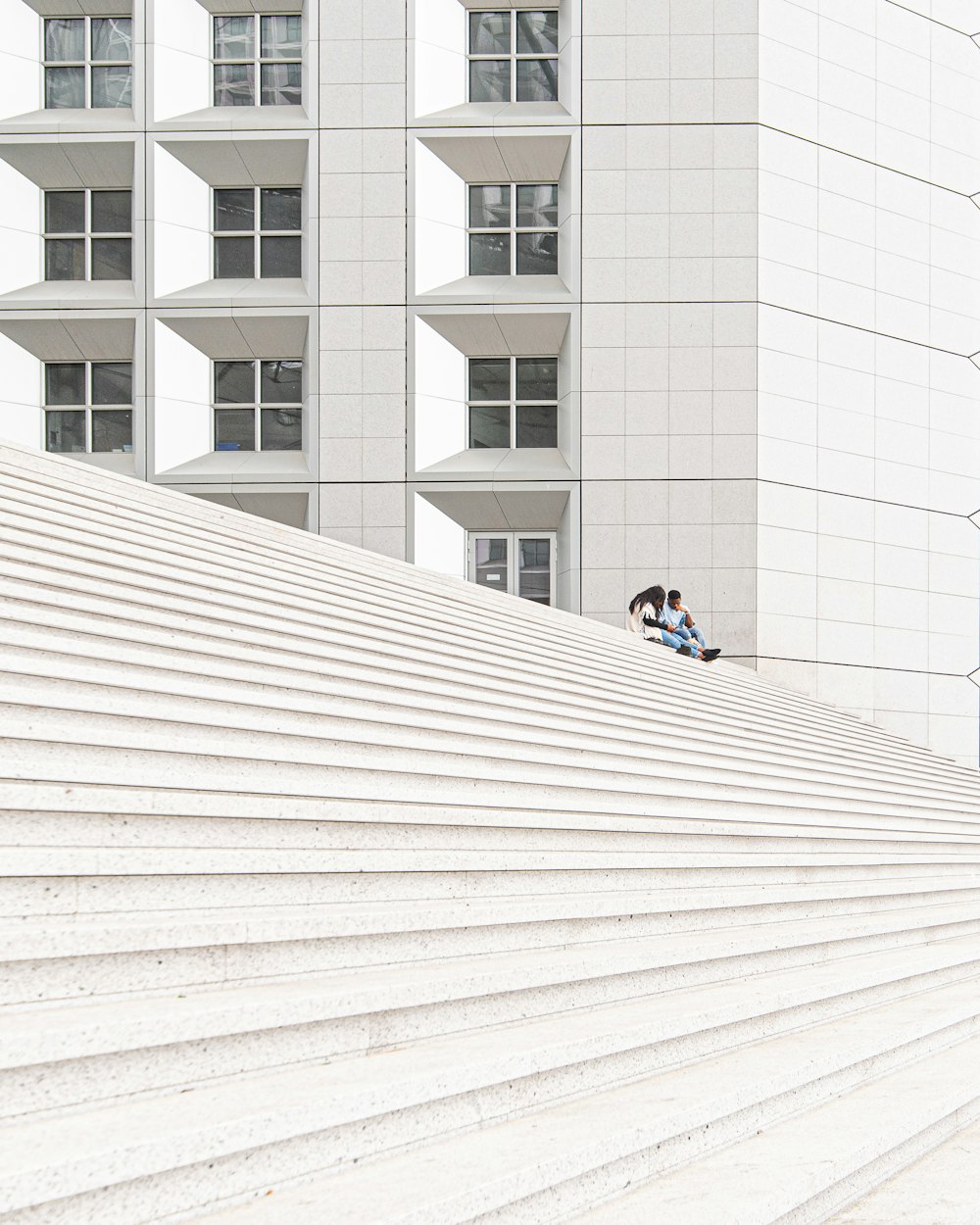 man in black jacket sitting on white concrete floor during daytime