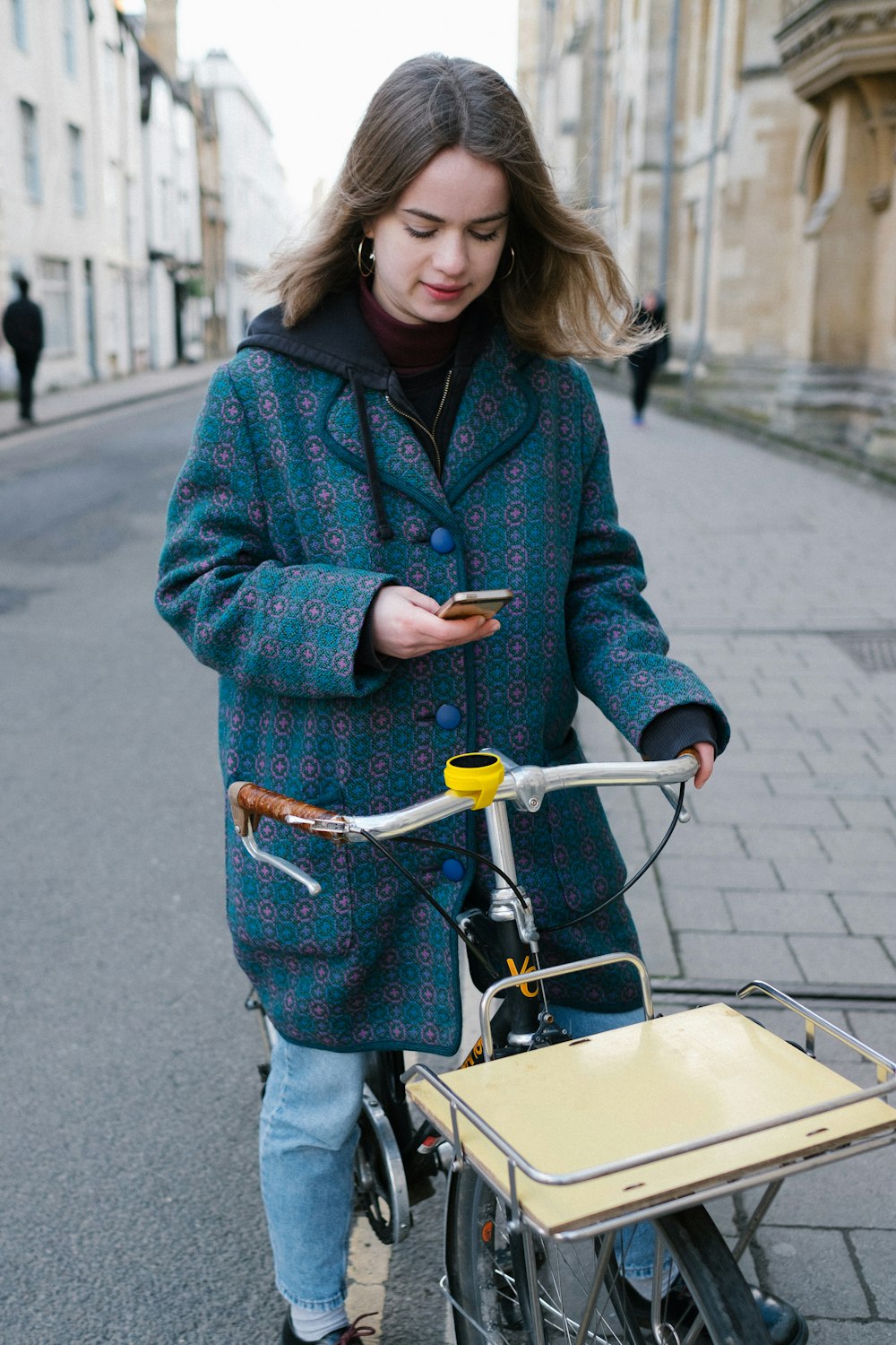 woman in red and black checkered coat and blue denim jeans holding yellow and black bicycle
