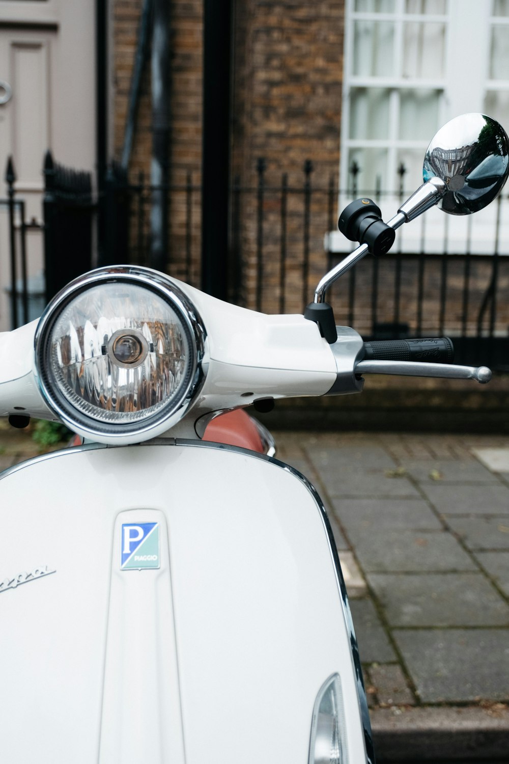 white and blue motor scooter parked beside brown brick wall