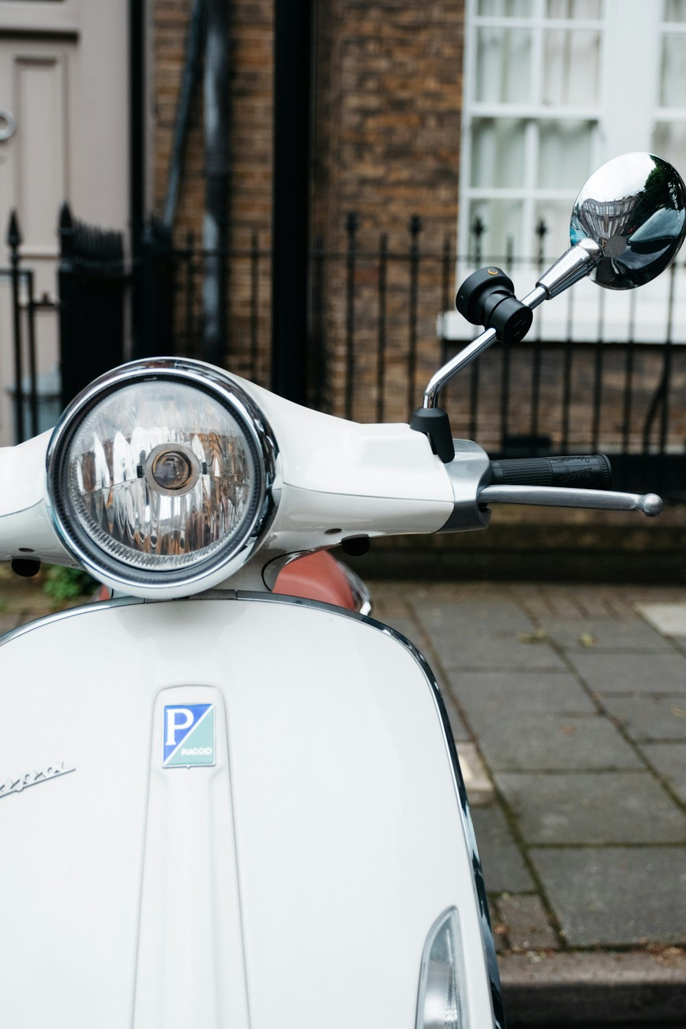 Scooter blanco y azul estacionado junto a una pared de ladrillos marrones