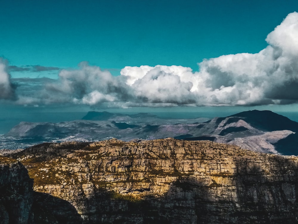 Montaña rocosa marrón bajo el cielo azul y nubes blancas durante el día