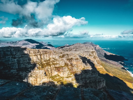 brown rocky mountain near body of water under blue sky during daytime in Table Mountain South Africa