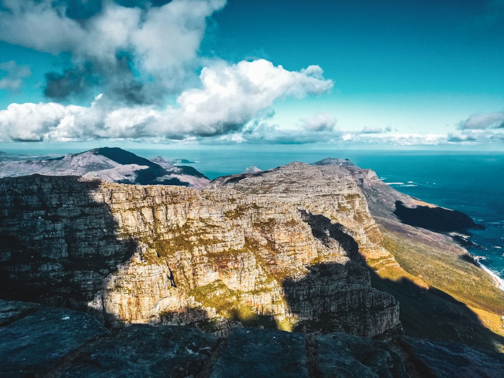 Montaña rocosa marrón cerca del cuerpo de agua bajo el cielo azul durante el día