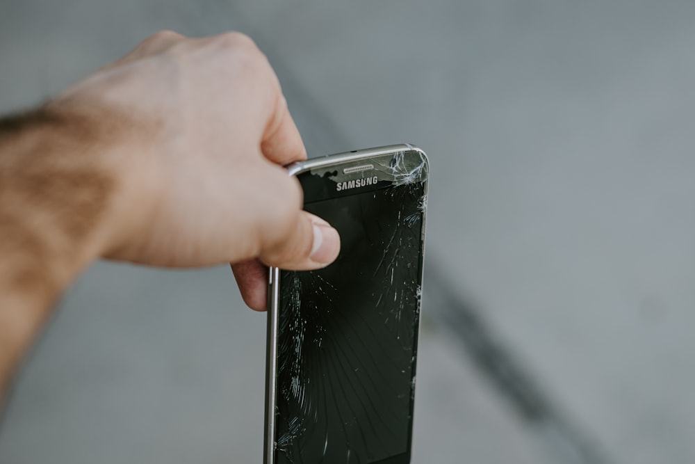 Persona sosteniendo un teléfono inteligente Samsung Android negro