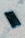 A smartphone with a cracked screen lies on a rough concrete surface. The cracks spread across most of the display, indicating significant damage.