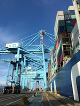 Wide view of a busy international port with ships and containers under a clear sky.