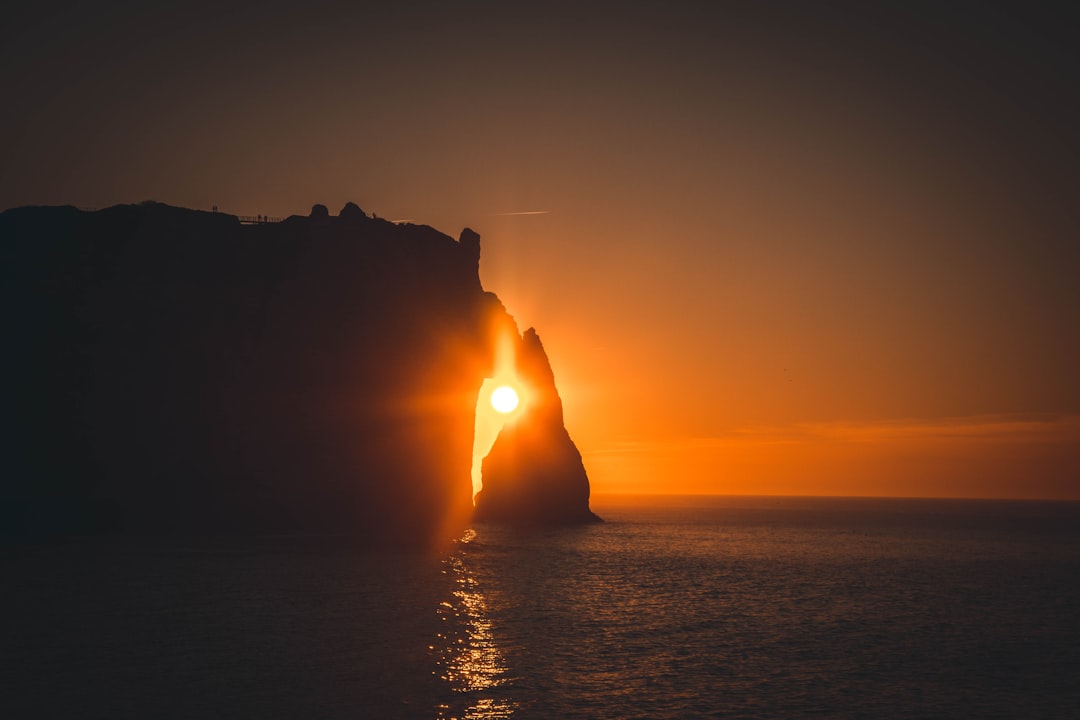 silhouette of a man on a cliff during sunset
