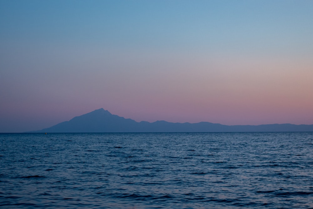 body of water near mountain during daytime